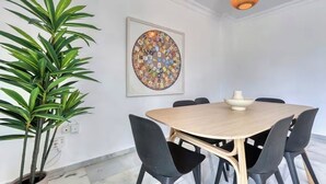 A conference room with a round table, black chairs, a potted plant, a framed artwork, and a hanging light fixture. - Apartment on the beachfront in Estepona, (Estepona)