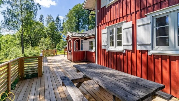 Ein rotes Holzgebäude mit einer Holzdiele und einem Picknicktisch.