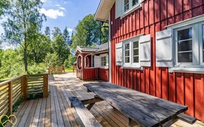 Ein rotes Holzgebäude mit einer Holzdiele und einem Picknicktisch.