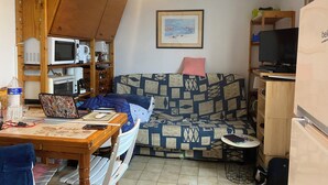 A compact living space with a wooden table, a sofa, a small round table, and a television. - Vacation home located 300m from the beach (Dolus-d'Oléron)