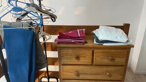 A wooden dresser with drawers, a bench, and a clothing rack with various garments. - Vacation home located 300m from the beach (Dolus-d'Oléron)