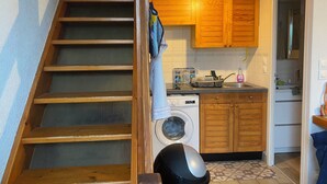 A kitchen with wooden cabinets, a washing machine, and a stove. - Vacation home located 300m from the beach (Dolus-d'Oléron)