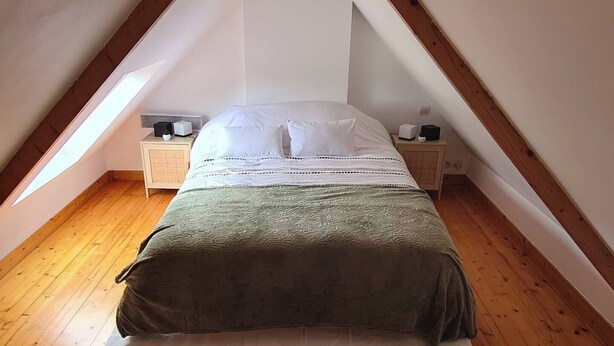 A small, cozy attic bedroom with a sloped ceiling, a single bed, a nightstand, and a wooden floor. - Atypical house at the entrance to Paimpol (Kerfot)