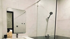 A modern bathroom with a glass-enclosed shower, a white sink, and a mirror above it. - Ben Ben Hotel (Xuan Huong - Da Lat)