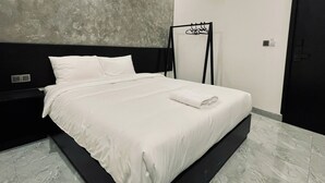 A modern hotel room with a large bed, a black headboard, a grey textured wall, and a black door. - Ben Ben Hotel (Xuan Huong - Da Lat)