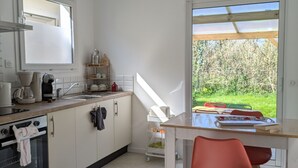 Eine moderne Küche mit weißen Schränken, einem eingebauten Backofen und einem Fenster mit Blick auf einen Garten.