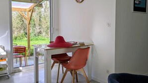 Ein Zimmer mit Tisch und Stühlen, einer Tür zu einem Garten und einem gerahmten Bild an der Wand.