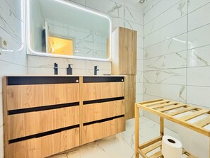 Ein Badezimmer mit einem Holzwaschtisch, einem Spiegel und einem Toilettenpapierhalter.