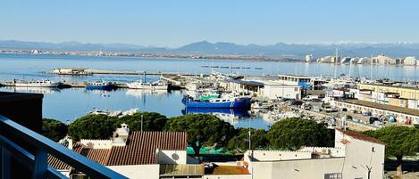 A marina with boats, buildings, and mountains in the background.