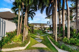 A modern hotel with a central courtyard, surrounded by palm trees and well-maintained gardens.