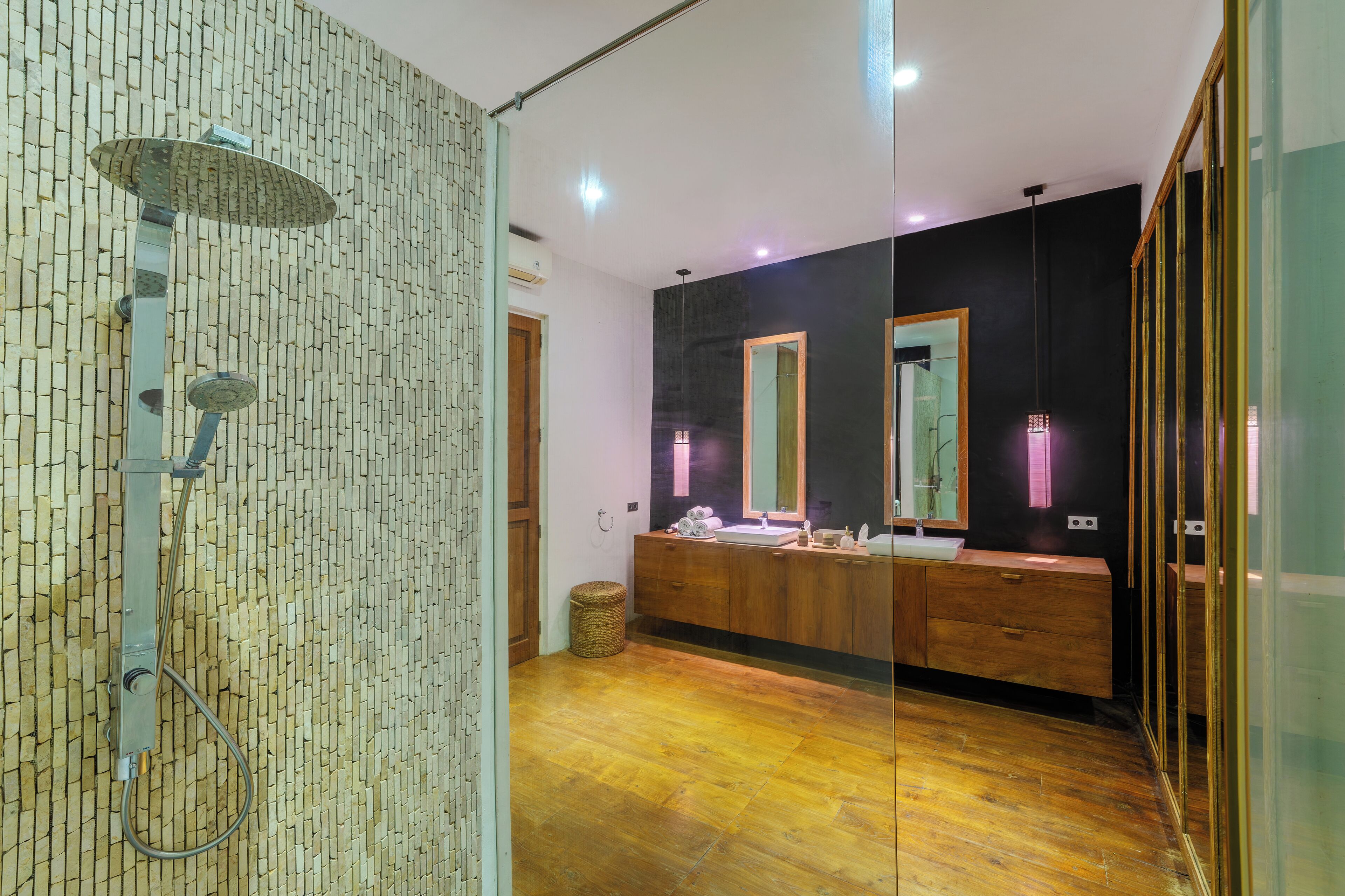 A modern bathroom with a glass shower enclosure, wooden vanity, and a large mirror.