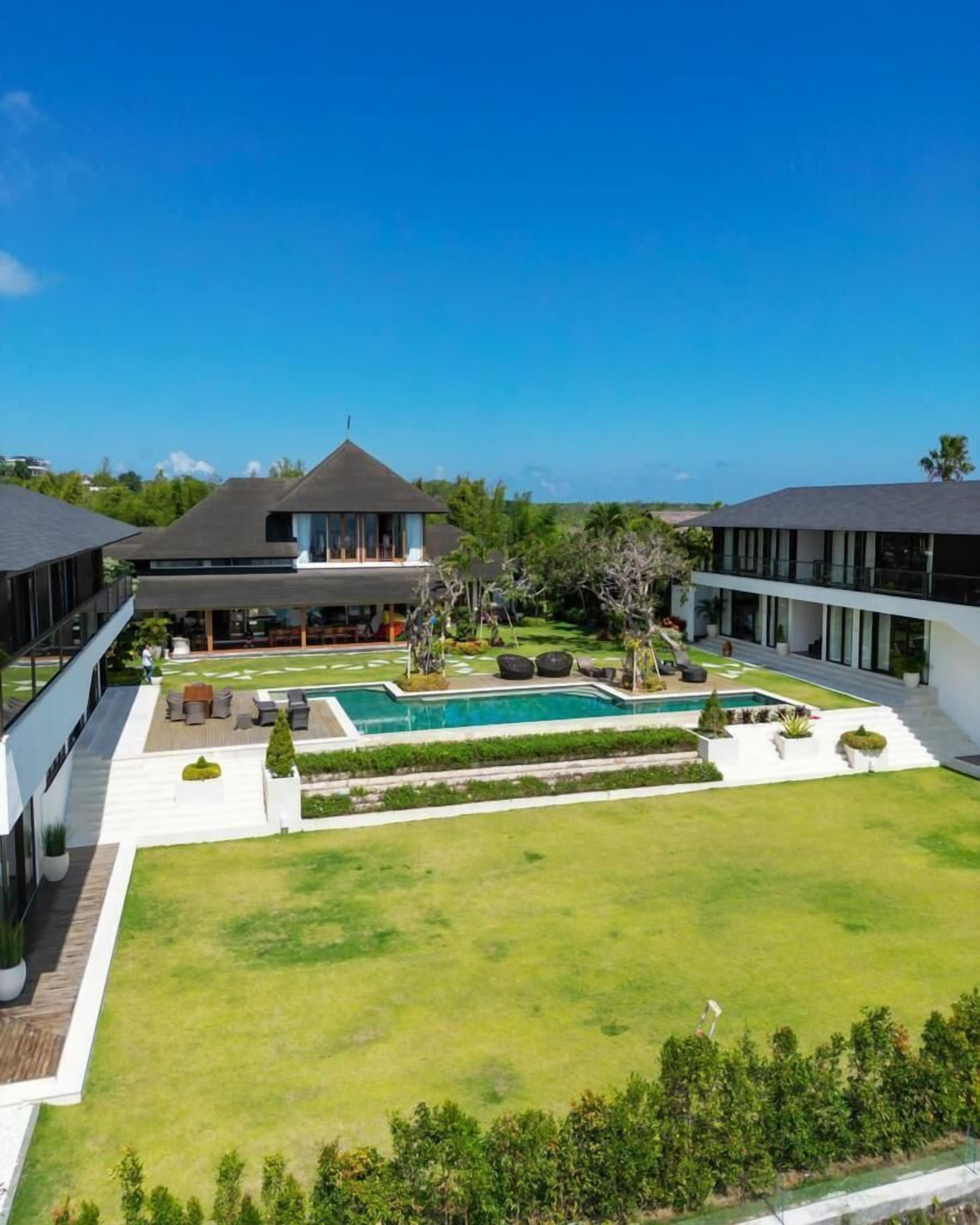 Un resort moderno con piscina, mobiliario exterior y abundante vegetación.