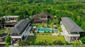 Un resort moderno con piscina central, varias habitaciones de huéspedes y exuberante vegetación circundante.