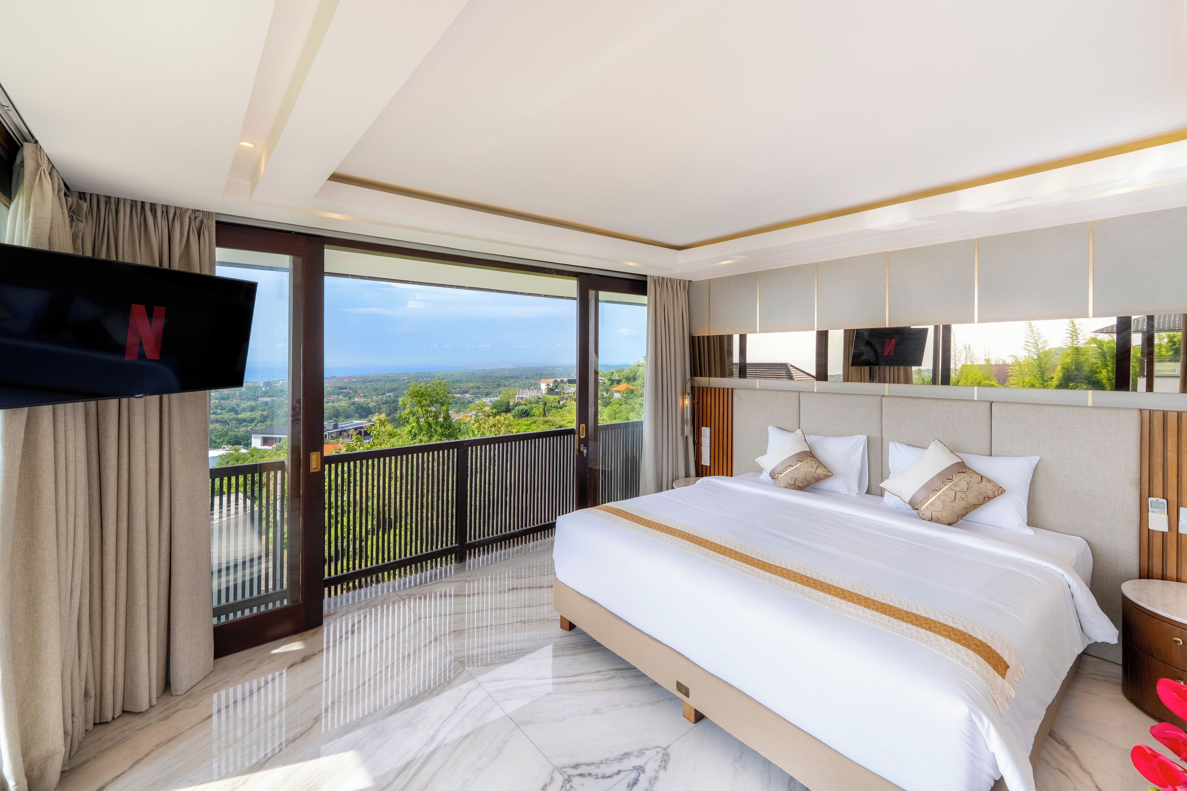 Camera d'albergo moderna con un letto grande, una TV a parete e un balcone con vista sulla città.