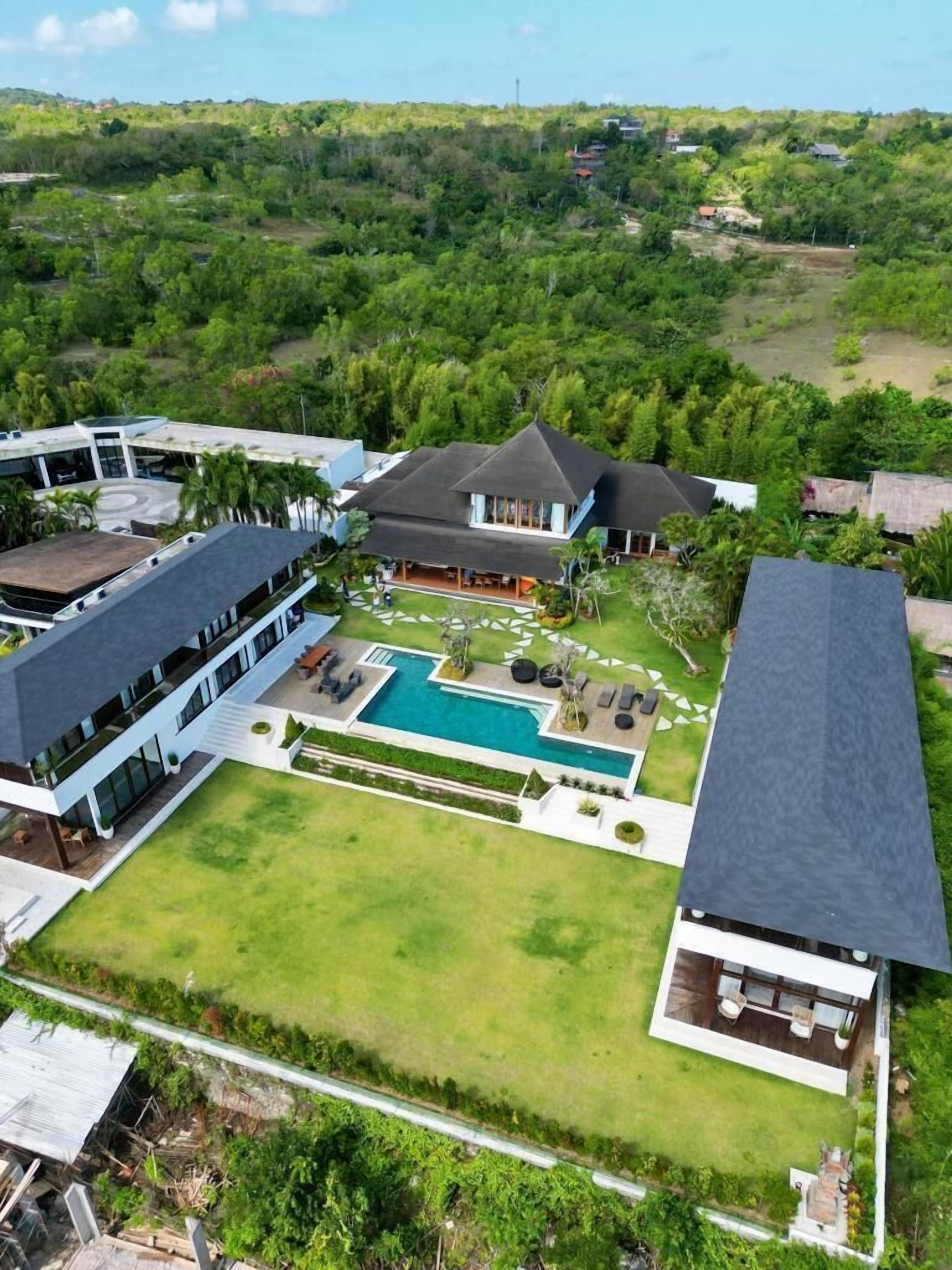 A modern resort with a central pool, multiple guest rooms, and lush greenery surrounding the property.