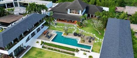 A modern resort with a central pool, multiple guest rooms, and lush greenery surrounding the property.
