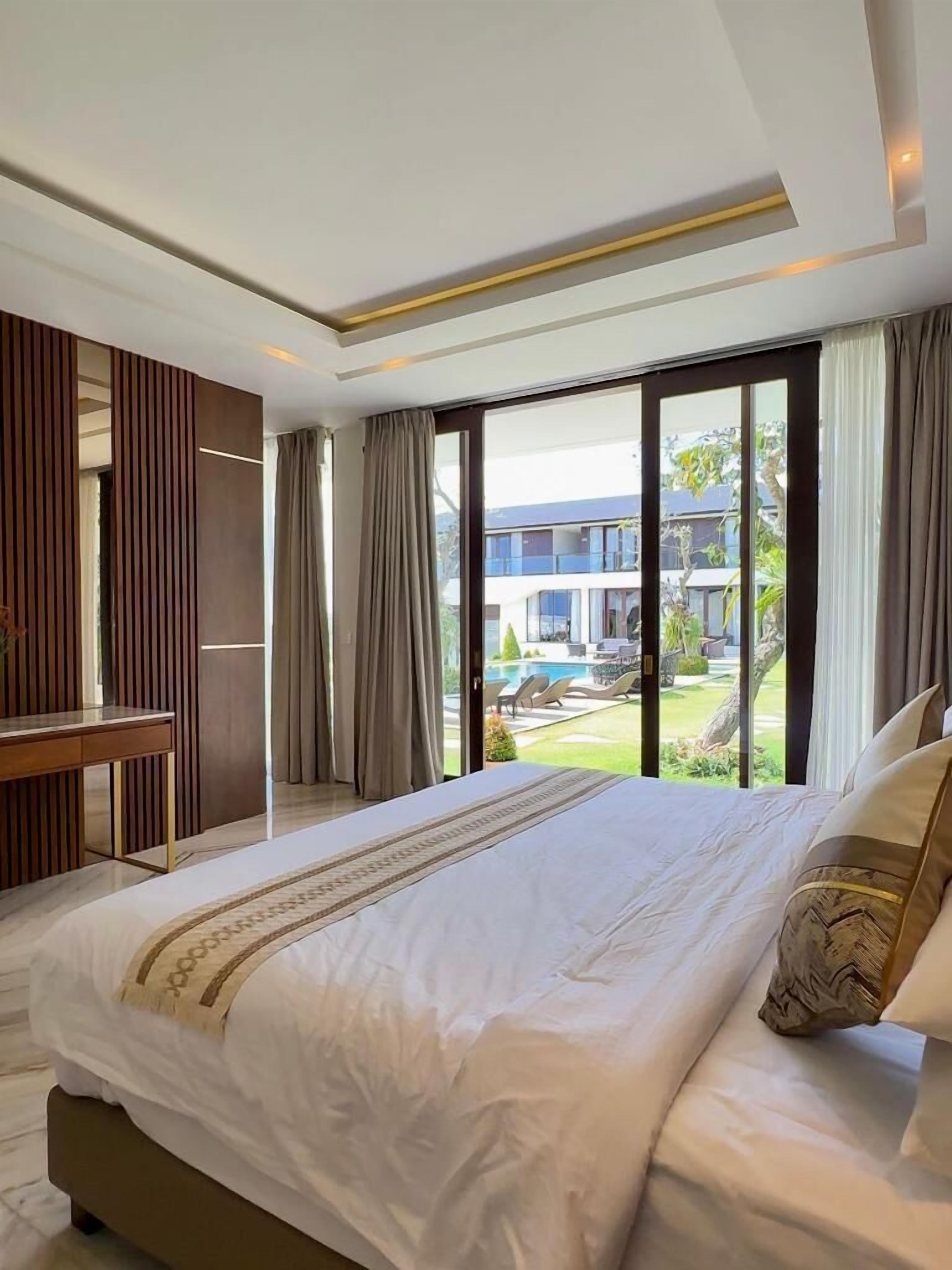 Una camera da letto moderna con un letto grande, una scrivania e vista su una piscina e un edificio.
