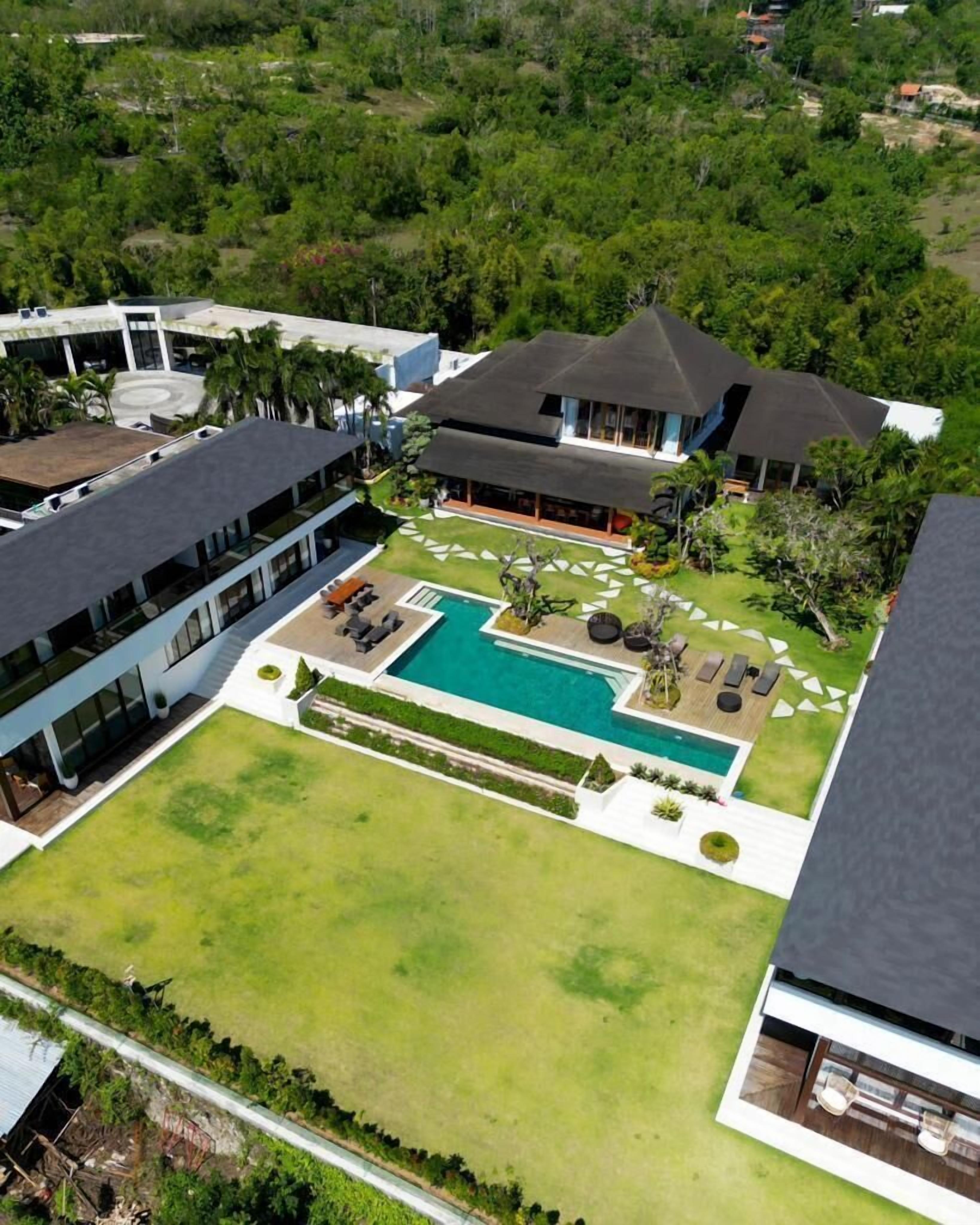 Un hotel moderno con piscina, mobiliario exterior y exuberante vegetación.
