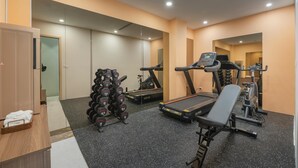 A gym with a treadmill, bench, and weight rack.