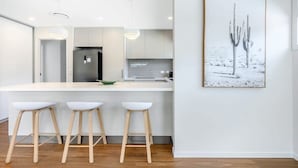 Uma cozinha moderna com uma ilha central, banquetas de bar e um quadro emoldurado na parede.