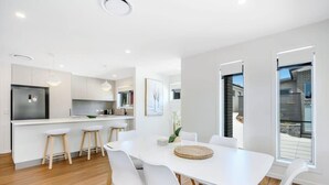 Uma cozinha moderna com armários brancos, uma ilha central e banquetas.