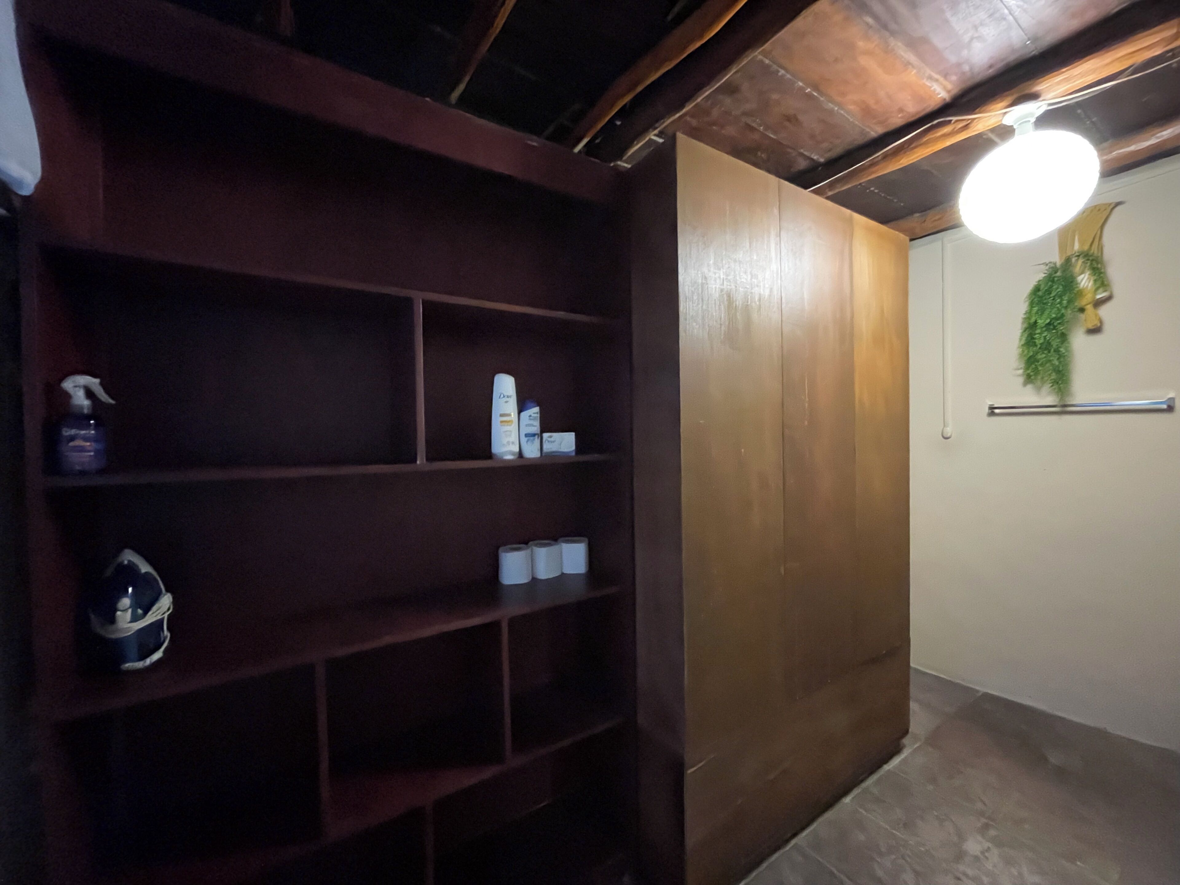 Una estantería de madera con artículos de aseo y un perchero para toallas.