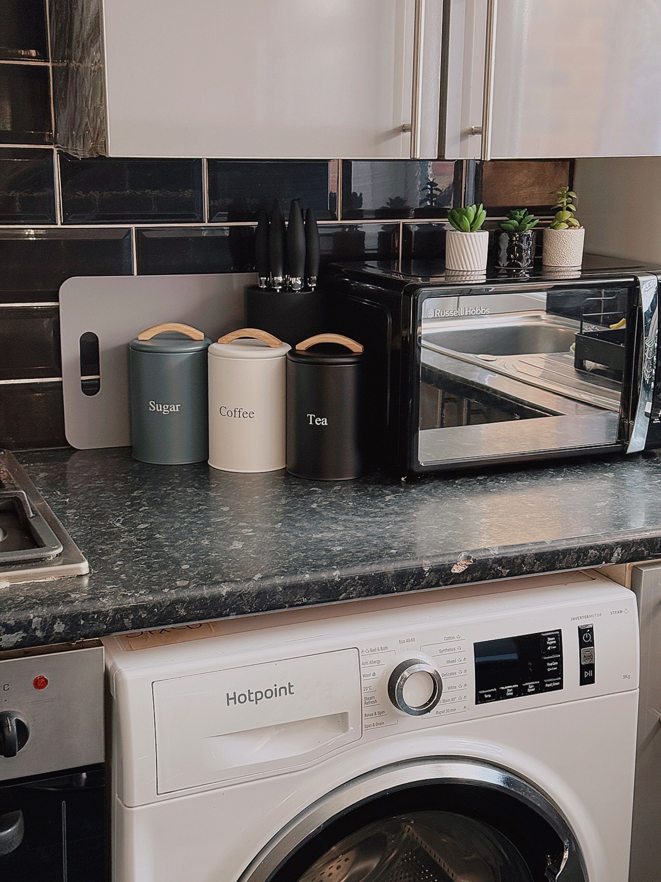 A kitchen with a microwave, a toaster, and a washing machine.