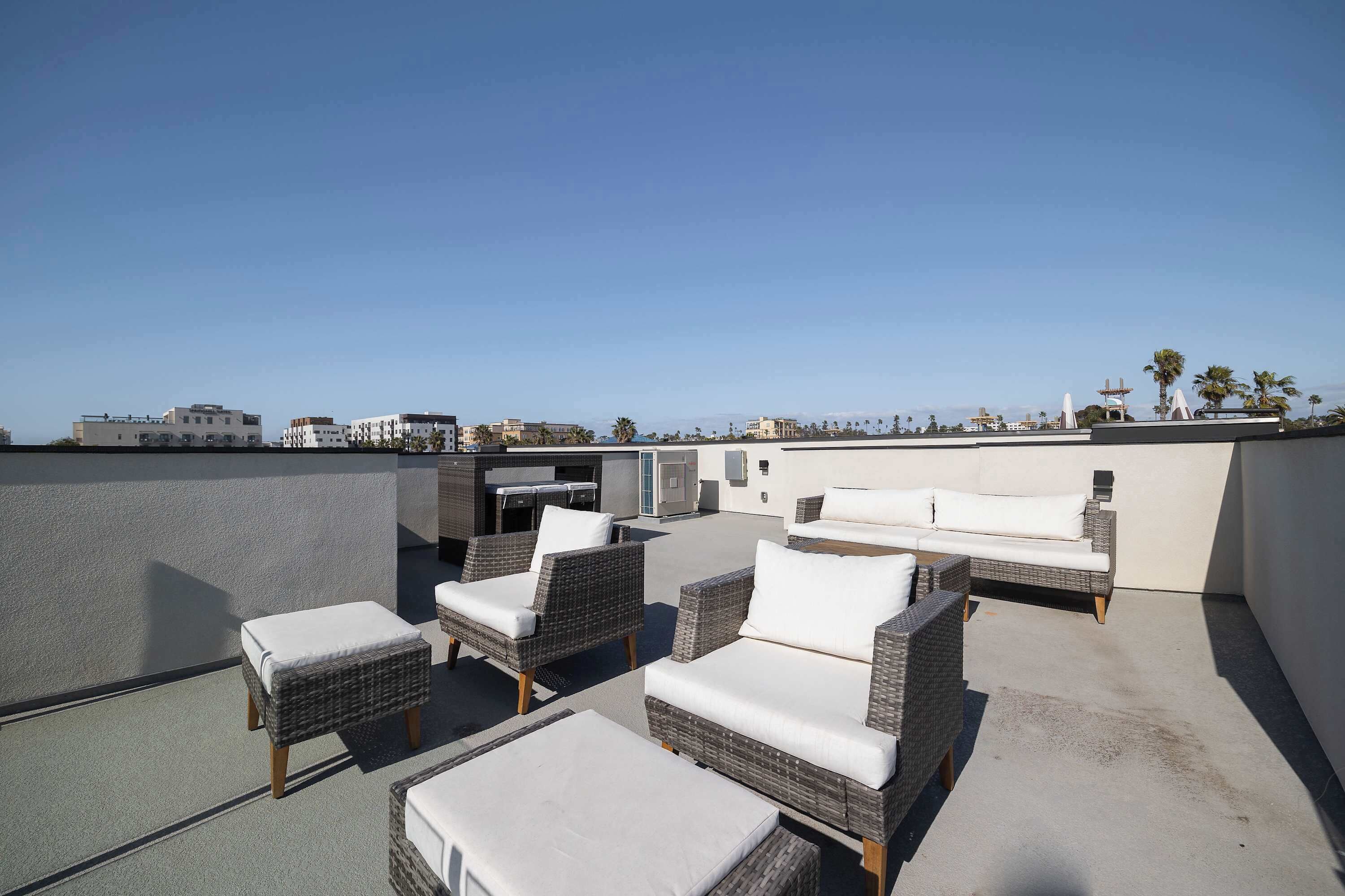 A rooftop terrace with wicker furniture, a table, and a view of the cityscape.