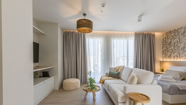 Una sala de estar moderna con un sofá, una mesa de centro y un televisor sobre un mueble.