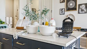 A kitchen counter with white bowls, a waffle maker, and a plant. - Music Row, Pool, Rooftop Deck, Balcony, Gym (Nashville)