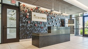 A reception desk with a sign reading "The Crescendo" in a modern lobby with patterned walls and a tiled floor. - Music Row, Pool, Rooftop Deck, Balcony, Gym (Nashville)