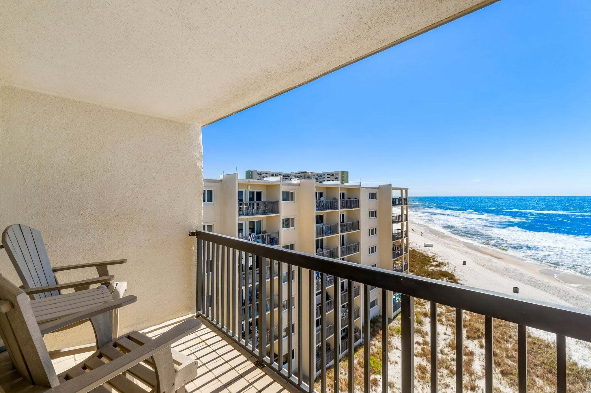 Un balcone con vista sulla spiaggia e un edificio a più piani.