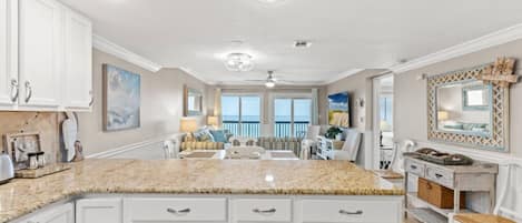 A spacious kitchen with white cabinetry, a granite countertop, and a large island.