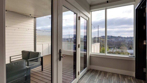 A balcony with a bench and a sliding glass door leading to an outdoor area.
