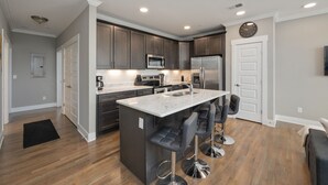 A modern kitchen with dark wood cabinets, stainless steel appliances, and a central island with bar stools.