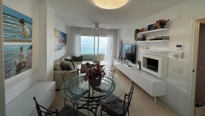 Un salon moderne avec une table à manger en verre, un canapé et un téléviseur.