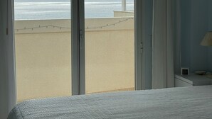 Une chambre avec une grande porte-fenêtre coulissante donnant sur la plage.