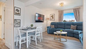 A modern living room with a dining table, sofa, and TV. - Golf Road Apartment | Grampian Lettings (Aberdeen)