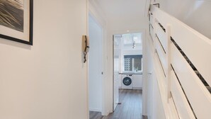A narrow hallway with a washing machine in the background, leading to a kitchen area. - Golf Road Apartment | Grampian Lettings (Aberdeen)