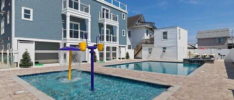 A pool area with a water feature and a multi-story building in the background.