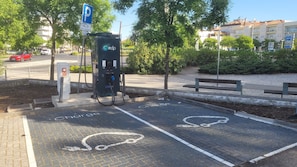 A parking area with electric vehicle charging stations, marked spaces for bicycles, and a blue parking sign. - StaynFeel 01 (Fátima)