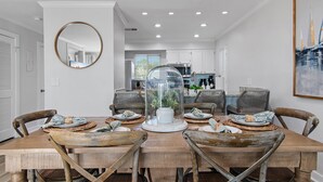 Un comedor con mesa de madera, sillas de mimbre y una lámpara colgante tipo cúpula de vidrio.