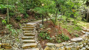 A stone pathway leading through a garden with a lamp post and a sign indicating the number 100.