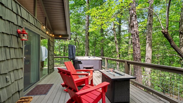 A deck with red Adirondack chairs, a grill, and a fire pit.