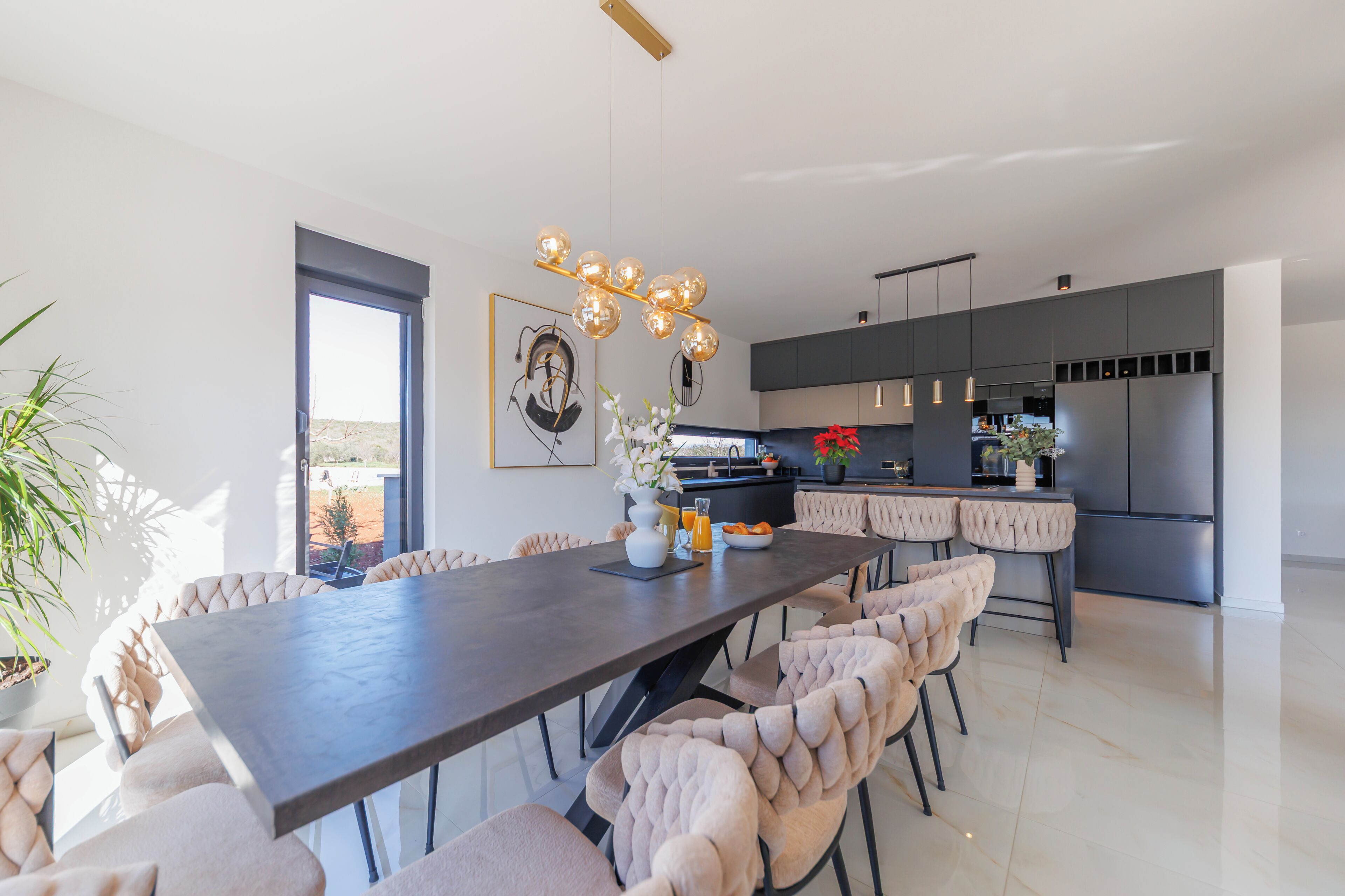 A modern kitchen with a dark countertop, stainless steel appliances, and a pendant light fixture.