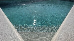 Piscina interna trasparente con bordo strutturato e superficie dell'acqua visibile.
