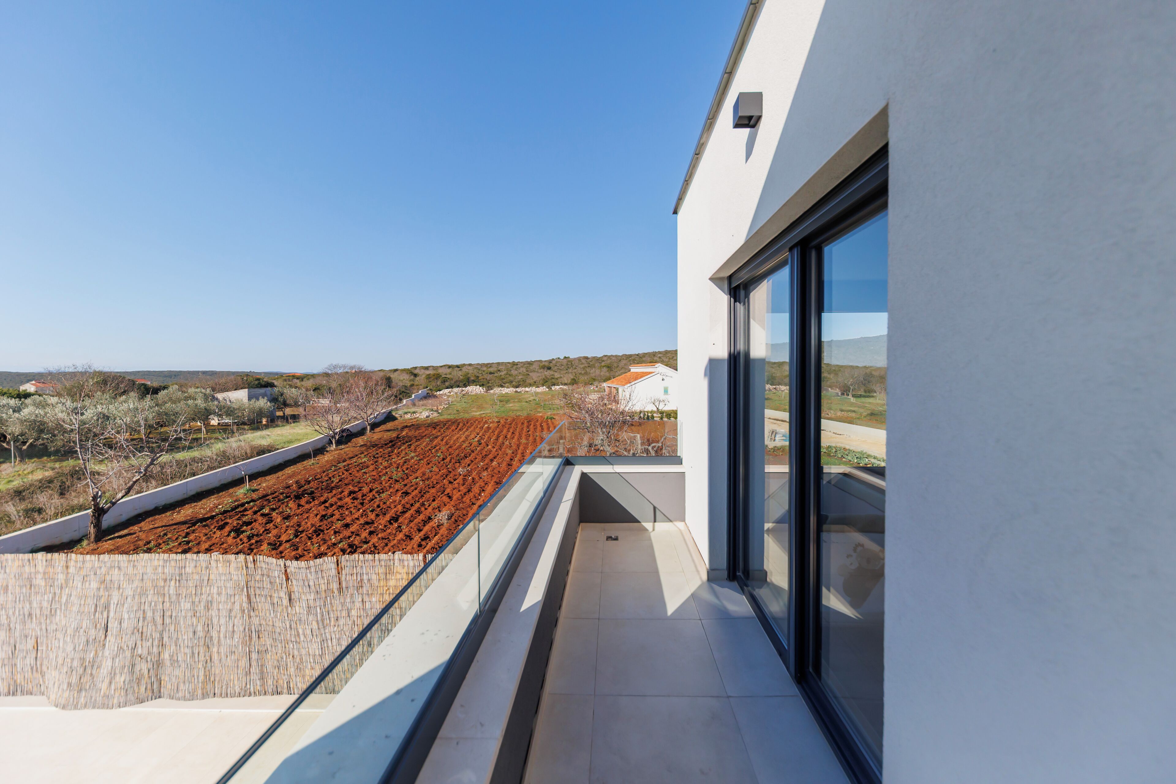 Ein Balkon mit Blick auf eine angelegte Grünfläche und entfernte Gebäude.