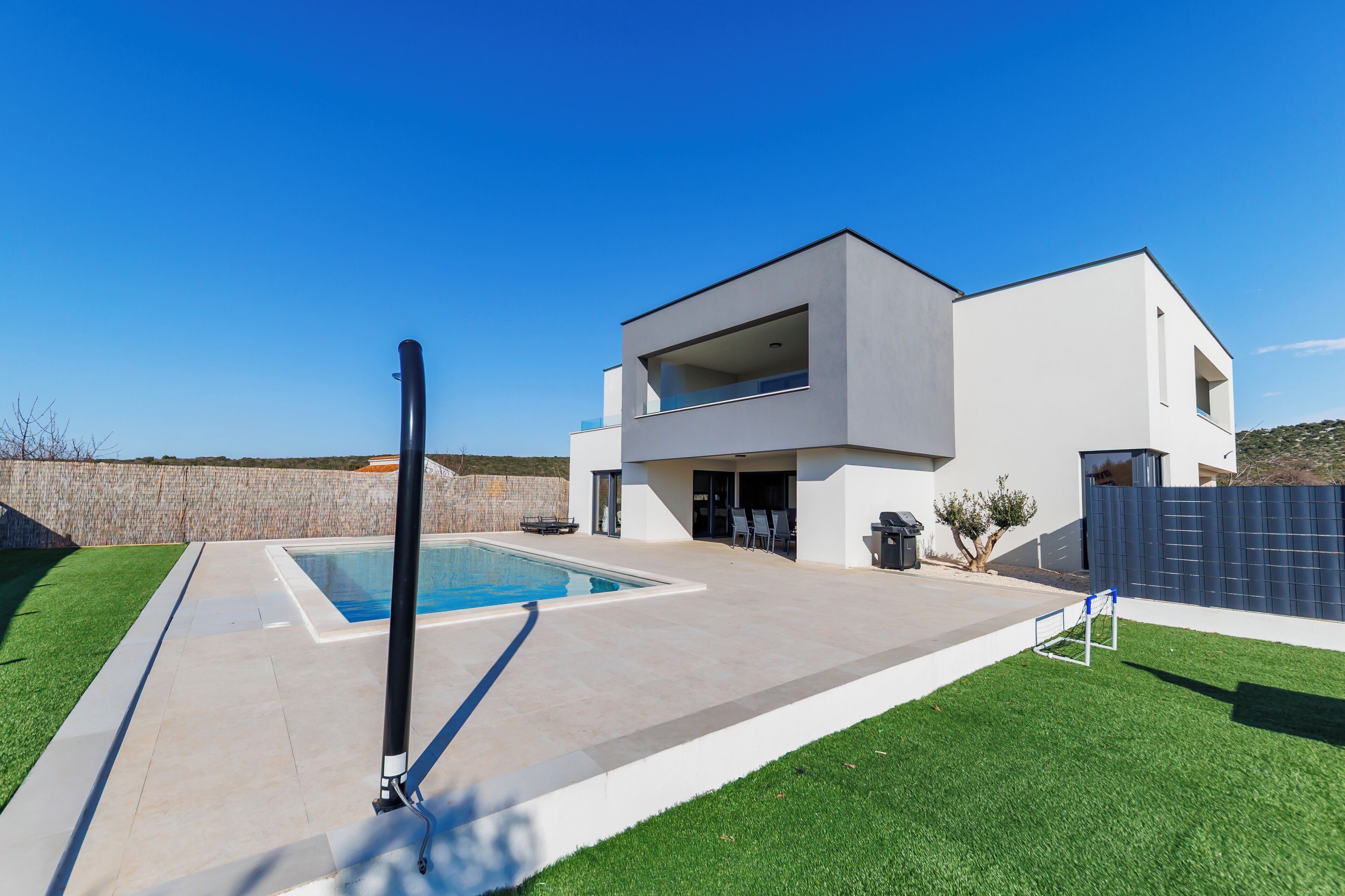 A modern two-story house with a swimming pool, a covered patio, and a fenced yard.