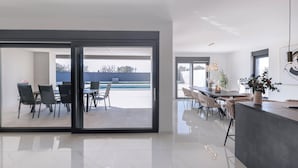 Una cucina moderna con una grande isola, porte scorrevoli in vetro che si aprono su una sala da pranzo con vista sul mare.