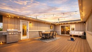 Un patio exterior techado con una parrilla, mesa de comedor y zona de estar.